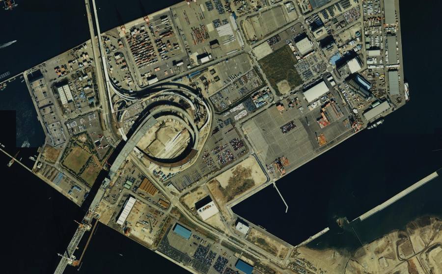 大黒ふ頭の建物の間に大きなループと建設途中の橋が見える航空写真